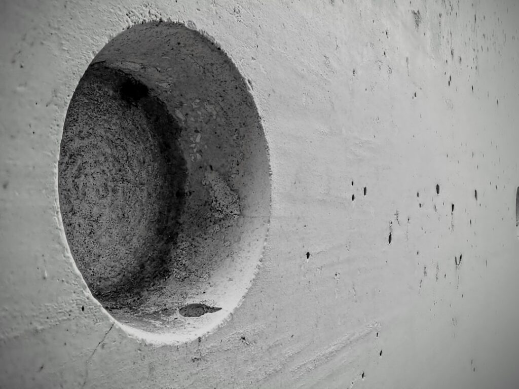 An abstract detail of cast concrete within the Tulach a’ tSolais 1798 memorial in County Wexford, Ireland. The circular recess and weathered surface emphasise material texture, shadow, and form, reflecting the monument’s minimalist architectural language and its quiet commemorative purpose.