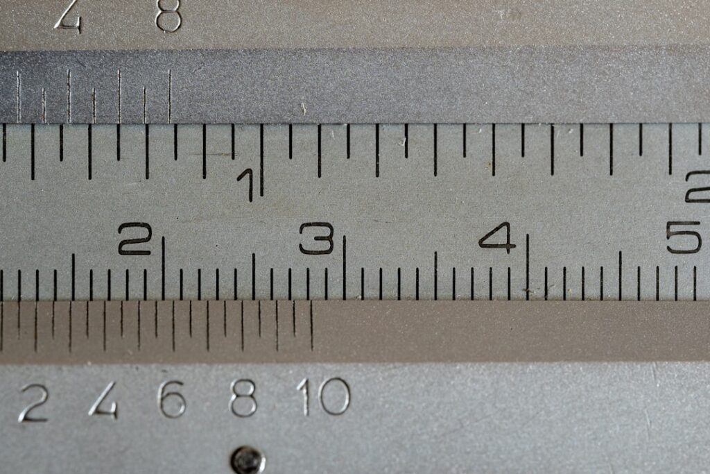 Close up of a vernier caliper ruler with visible markers for 1 in, 2 cm, 3 cm, 4 cm, and 5 cm