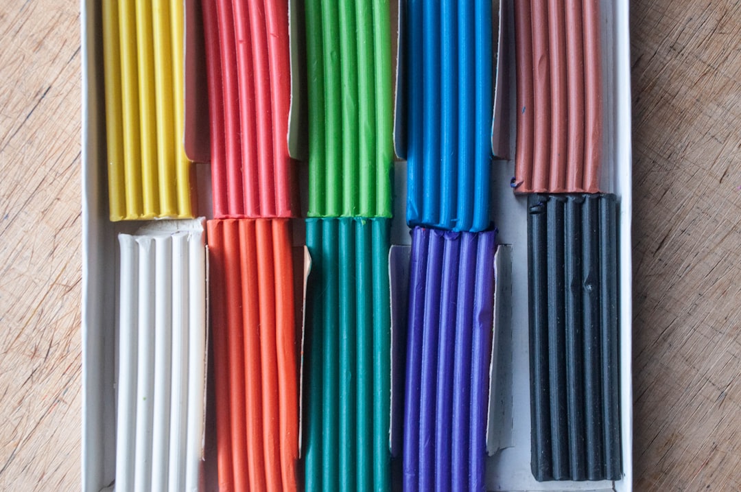 Top view box of colorful plasticine on wooden table background. Modelling clay package.