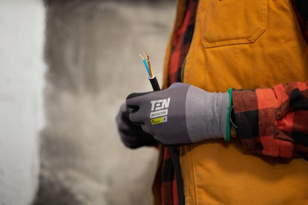 An electrician with work gloves holding a wire.